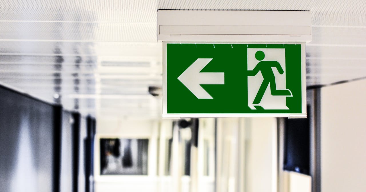 Green emergency exit sign with directional arrow in a hallway.