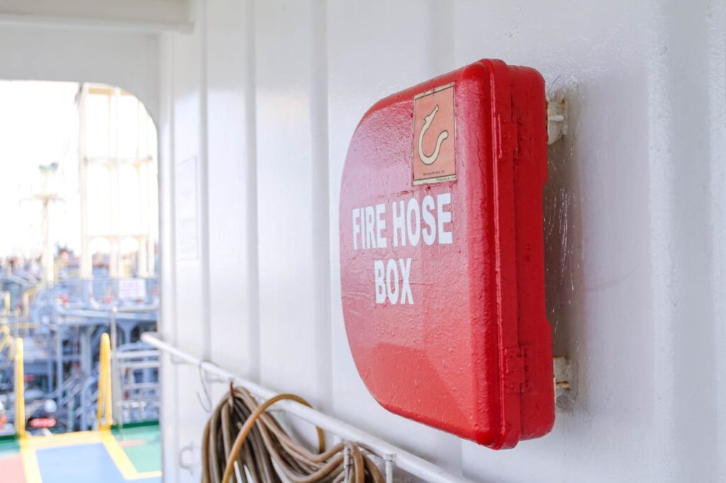 Close-up of a bright red fire hose box on a ship deck, emphasizing safety.